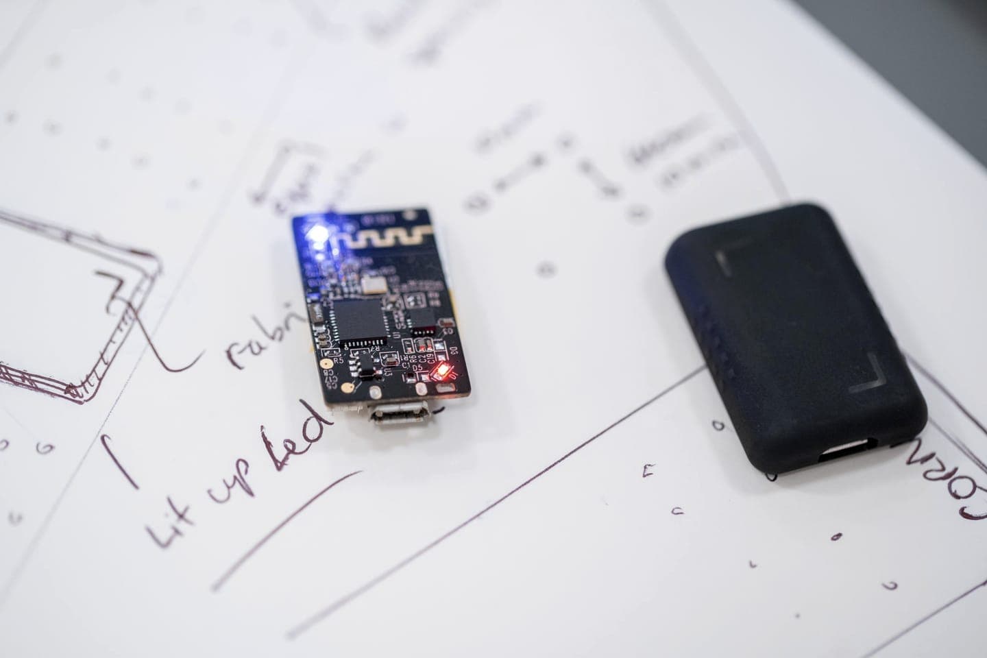 A prototype circuit board and a small smart device on design sketches