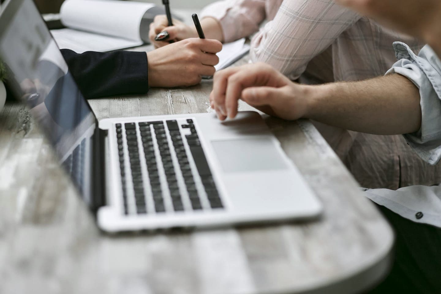 Two people working together at a laptop, with notes on the table